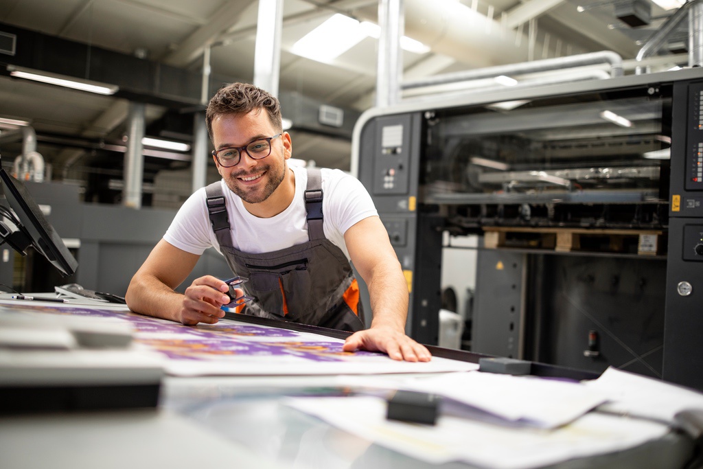 Coated vs. Uncoated Paper: What’s the Difference? 2 Print house worker controlling printing process quality and checking colors with magnifying glass.