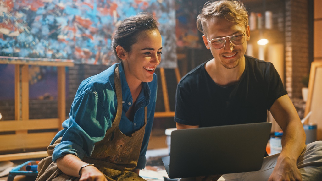 Turn Your Original Artwork Into an Online Store Like Etsy 2 Artists in studio using laptop to organize print-ready design files before selling their work online